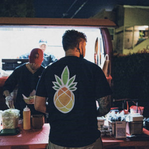 man with arm tattoo in black shirt pineapple logo